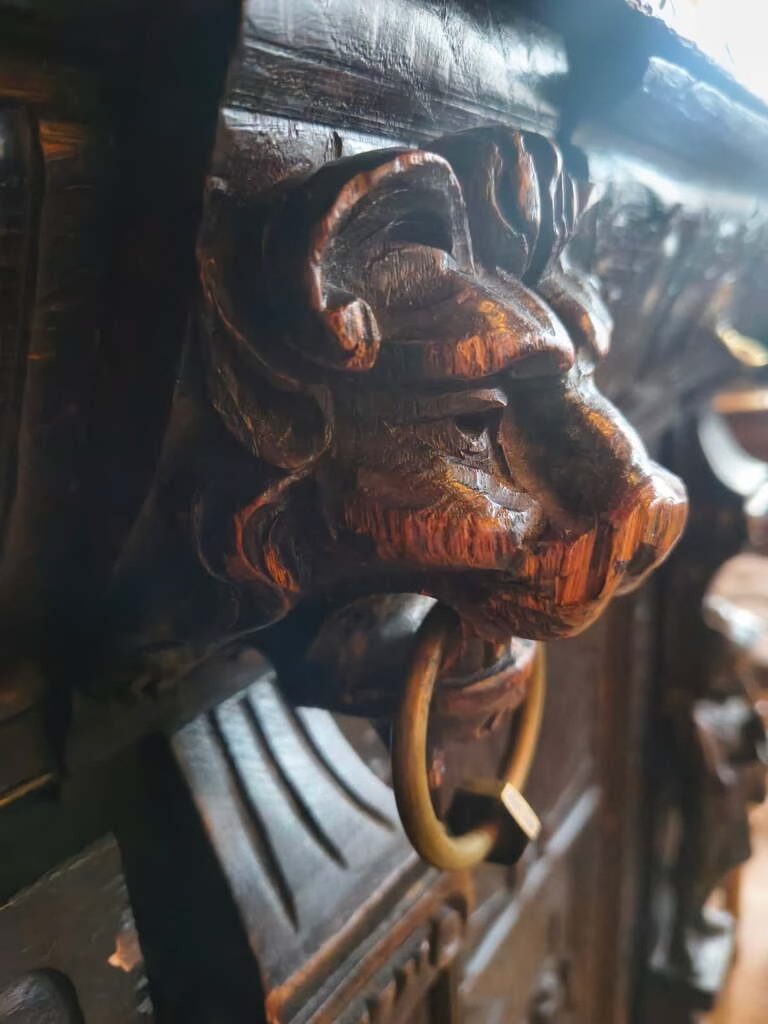 Hand-carved lion's head with brass ring on an antique door