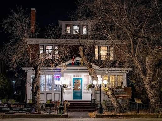 The house lit warmly at night from the street