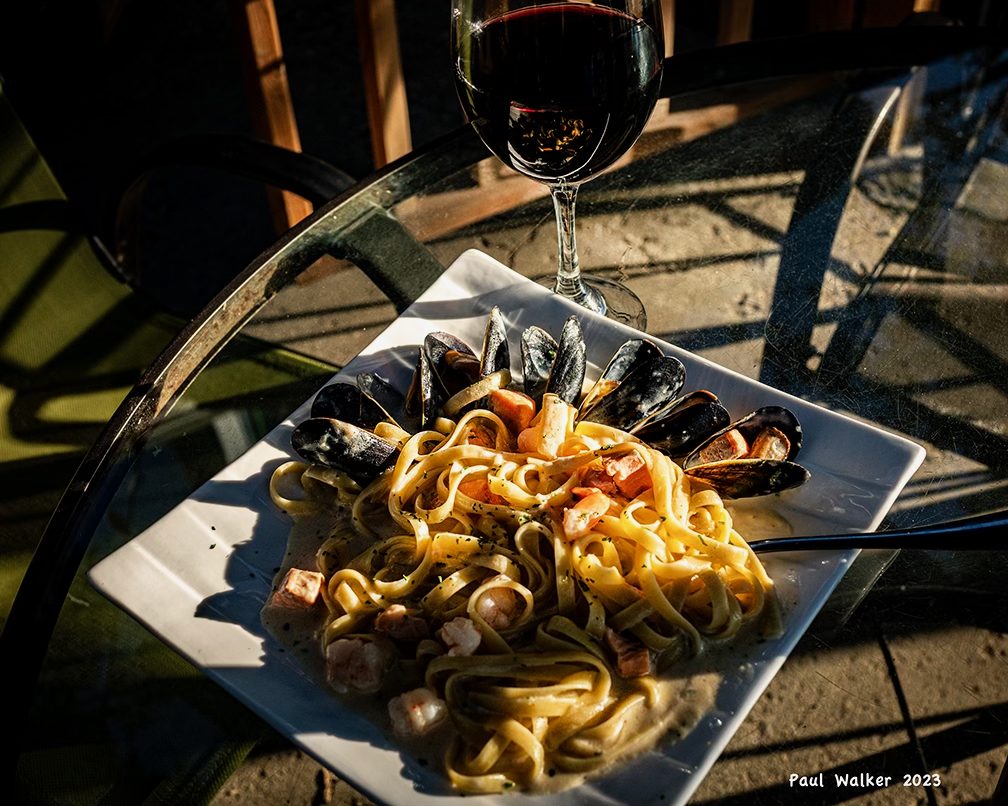 Seafood fettuccini with a glass of red wine on the patio